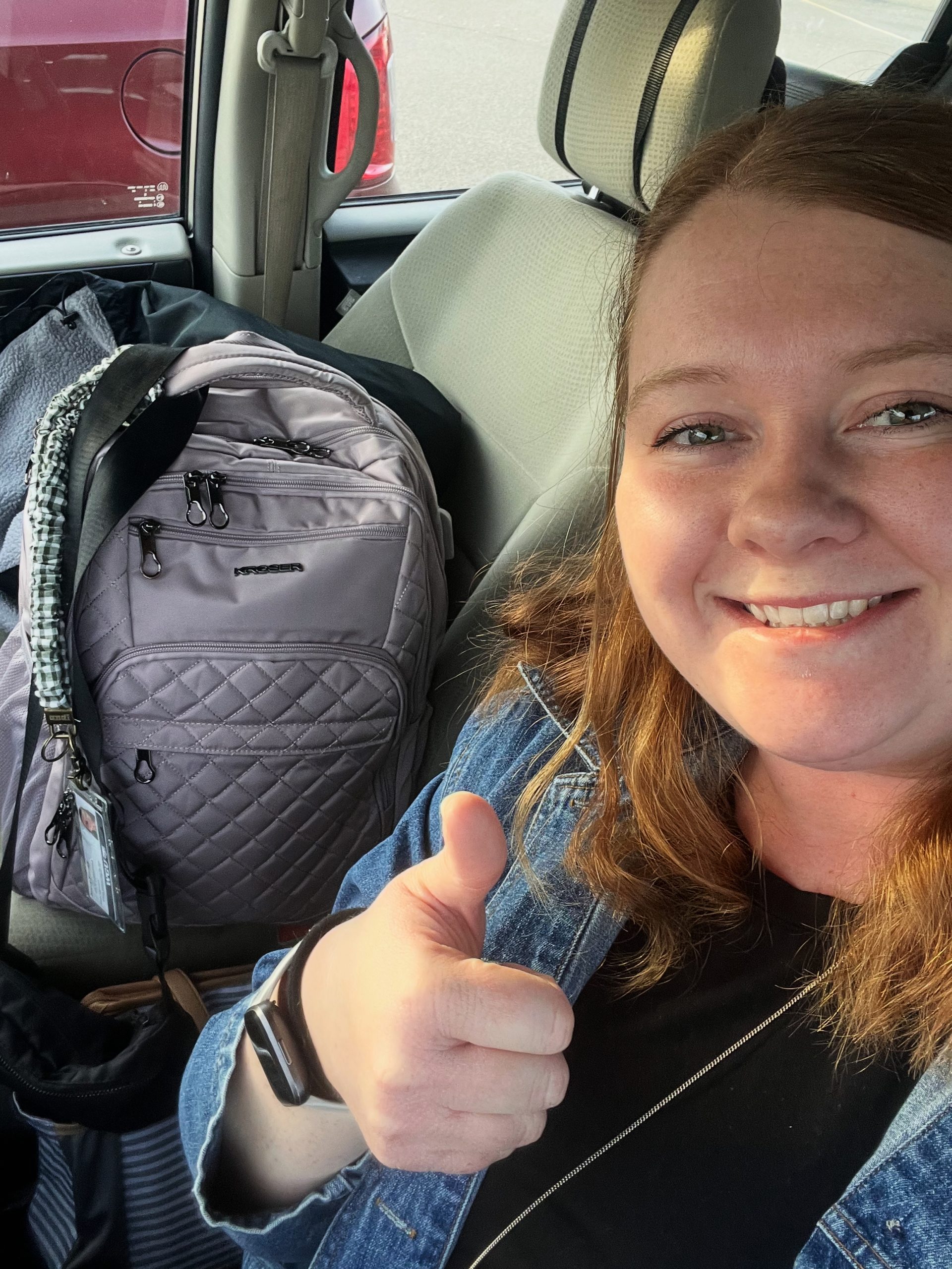woman giving a thumbs up with a back pack on her way to her first day of student teaching